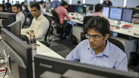 Getty Images Employees work on computers in an office in India