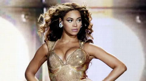 Getty Images Beyoncé, pictured in 2009, glances to the side of the stage as she performs in a sparkling gold body suit