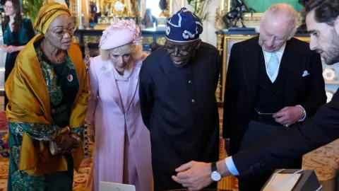 PA Media The President and First Lady of Nigeria stand alongside King Charles and Queen Camilla as they look at items on display 