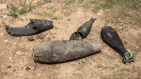 AFP via Getty Images Five pieces of black shrapnel lie on a dusty ground