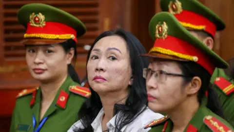 EPA Truong My Lan, centre, with two guards either side of her while in court.