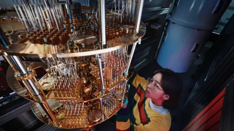 Alice & Bob A technician works on part of the Alice and Bob quantum computer. It looks like a large chandelier.