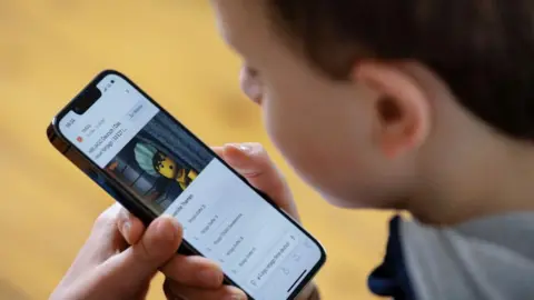 Photothek via Getty Images A boy plays with a mobile phone