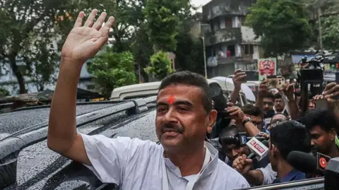 Getty Images BJP leader Suvendu Adhikari seen stepping out of a black car as he visits a polling station in Kolkata April 29, 2026. He wears a white collarless shirt and has a saffron mark on his forehead.