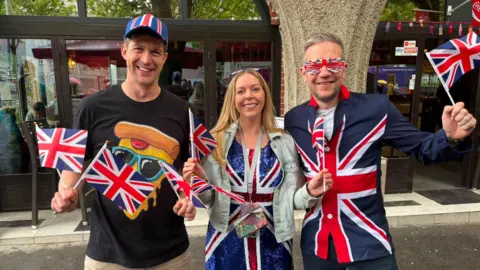 British Eurovision fans Sam Watkinson, Vicky Larke and Liam Larke wave flags on the streets of Vienna