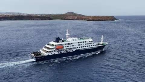 Reuters A drone view of the cruise ship MV Hondius, carrying passengers suspected of having cases of hantavirus on board, leaving Cape Verde on 6 May.