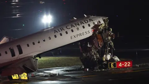 AFP via Getty Images A plane with a sheared off nose on the runway. It is night. 