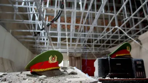Lulu Luo/BBC Vietnamese police caps coated with dust in one of the many rooms in Royal Hill Casino
