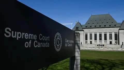 NurPhoto via Getty Images The Supreme Court of Canada sign in the foreground with the court building behind it. 