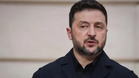 EPA Ukrainian President Volodymyr Zelensky speaks during a joint press conference with the French president following their talks at the Elysee Palace in Paris, France, 13 March 2026. He's wearing a black suit, as he always does.