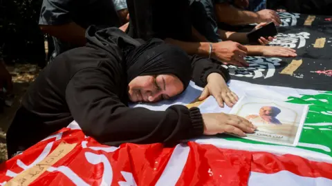 Reuters A woman leans over a casket during the funeral of two parents and their four children in an Israeli strike, in Wardaniyeh, Lebanon (3 June 2026).
