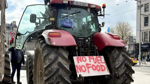 Reuters A large red tractor from behind - a white placard with red paint sits between the back wheels. The paint reads 