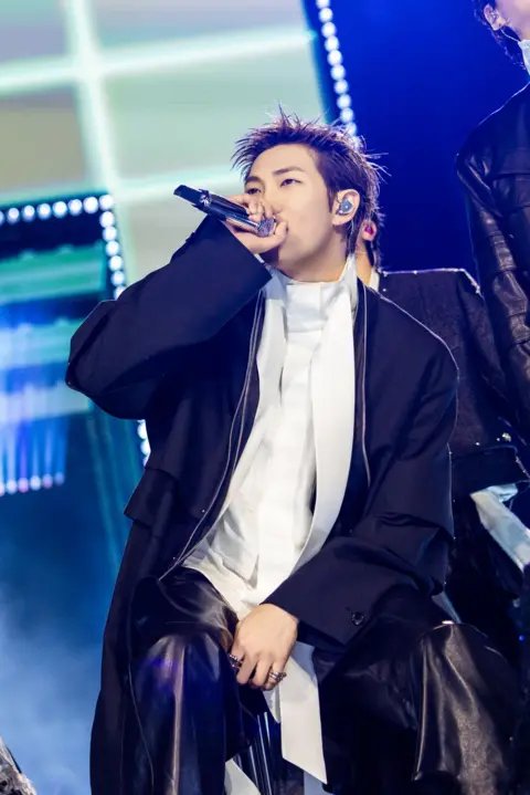 BIGHIT MUSIC AND NETFLIX Vertical shot of band member during concert