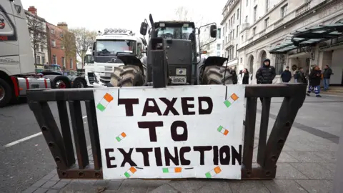 PA Media A sign that says taxed to extinction on the front of a tractor 