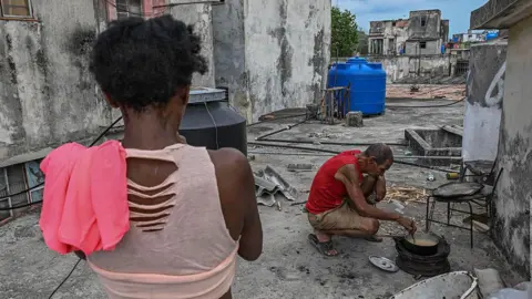 AFP via Getty Images A man cooks with firewood during a blackout in Havana on May 13, 2026. 