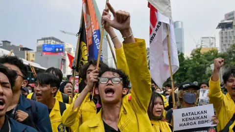 Getty Images An Indonesian student protester wearing yellow marching on the street in Jakarta with one arm raised