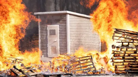 Fort/submitted photo A small grey shed is surrounded by flames, but does not burn
