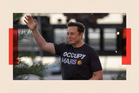 Getty Images Elon Musk walks on stage as he wears a top that reads: "Occupy Mars."