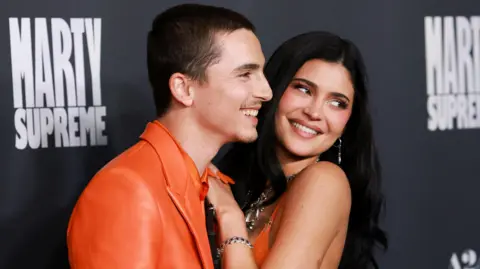 Reuters Timothee Chalamet in a bright orange suit with Kylie Jenner in a matching orange dress, cosying up and smiling at the premiere