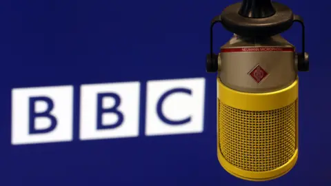 Getty Images A white BBC logo on a dark blue background, with a yellow vintage-style microphone in the foreground