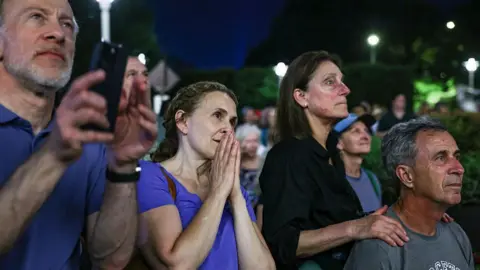 Bloomberg via Getty Images a group of people watching in anticipation in front of the Kennedy Center