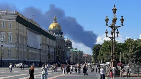 Getty Images Smoke seen rising in the background of a scene from St Petersburg with a wide street and historic buildings