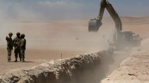 Reuters Members of the Chilean army stand near a trench dug by heavy machinery in the desert.