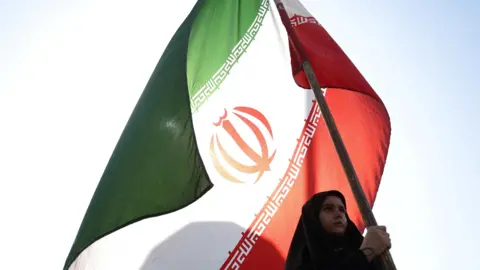 Reuters A woman holds an Iranian flag on a street in Tehran, Iran.