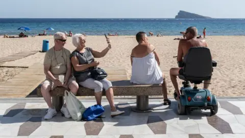 AFP via Getty Images Tourists next to the main beach in Benidorm