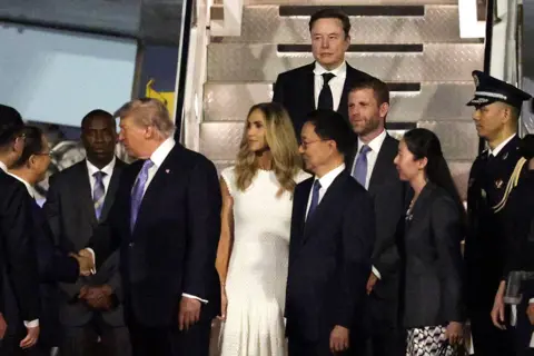 Getty Images SpaceX CEO Elon Musk, Eric Trump and Lara Trump depart Air Force One as U.S. President Donald Trump greets a local official upon arrival at Beijing Capital International Airport on May 13, 2026 in Beijing, China.