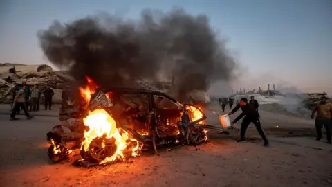 EPA A Palestinian man attempts to put out the fire that engulfed a car after an Israeli drone strike the killed Mohammed Wishah, a correspondent for Al Jazeera Mubasher, and one other person, in Gaza City, northern Gaza (8 April 2026)