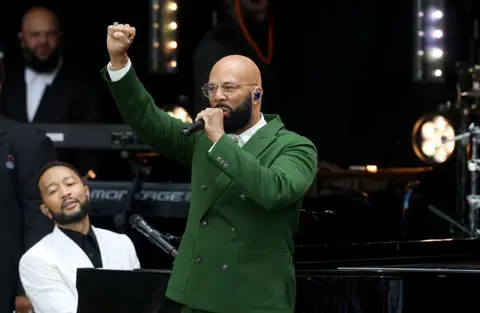Getty Images Award-winning rapper Common performs onstage while John Legend plays piano at the Obama Presidential Center in Chicago.
