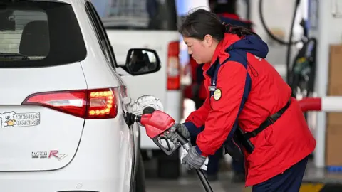 Getty Images A worker refills a car at a gas station in Nanjing in eastern China's Jiangsu Province, Monday