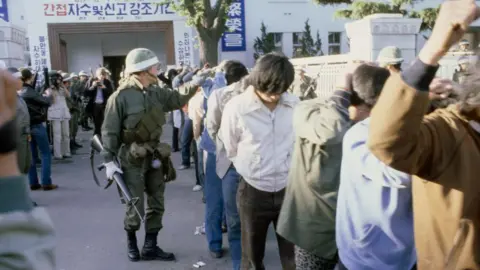 Getty Images Armed South Korean troops round up protestors - who have their hands on their heads - following a raid in the city of Gwangju after the uprising in 1980.