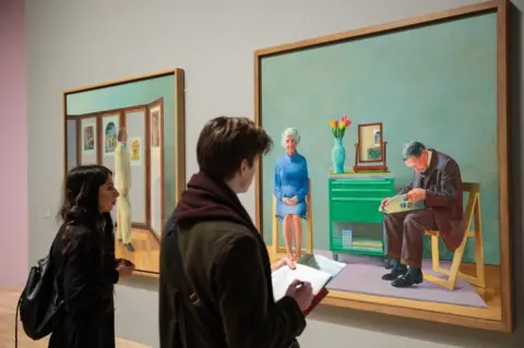 Getty Images David Hockney's painting of his parents. This photo shows gallery goers looking at Hockney paintings. 