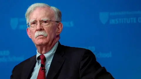 Getty Images Former Trump national security advisor John Bolton appears against a blue background while sitting on a panel.