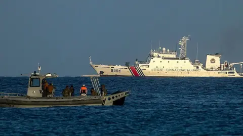 Getty Images A Philippine Marine speedboat patrols off the coast of Manila-ruled Thitu Island while a China Coast Guard vessel nears it, in the disputed South China Sea, on May 3, 2026. The Philippine-ruled Thitu Island, also known as Pagasa, is part of the Spratly Island groups in the South China Sea, disputed by neighboring countries including Beijing, Manila and Vietnam.