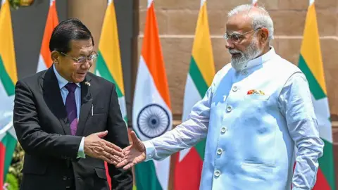 Getty Images Indian PM Narendra Modi (right), wearing a white bandhgala, shakes hand with Myanmar President Min Aung Hlaing, wearing black suit and tie over shirt in Delhi's Hyderabad House, on June 1.