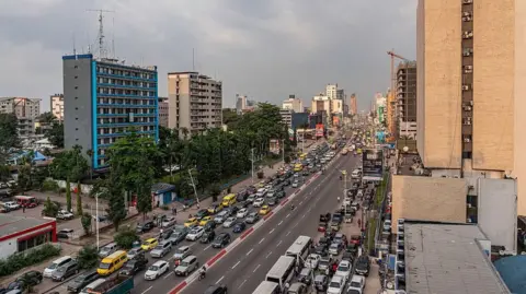 Getty Images Surrounded by high-rise buildings, Kinshasa's Boulevard du 30 Juin is busy with traffic.