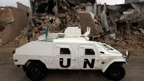 EPA An armoured vehicle of the United Nations Interim Force in Lebanon (UNIFIL) drives next to destroyed buildings in Meiss al-Jabal, Marjayoun district, southern Lebanon, 08 December 2025.