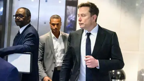 Getty Images Musk appears walking into the courthouse wearing a black suit and tie with a white shirt