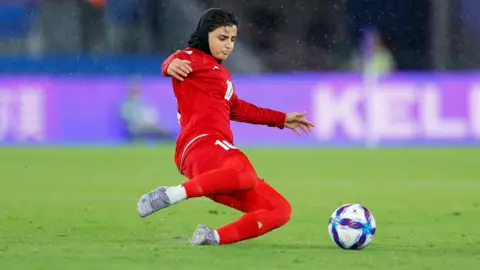 Getty Images A woman in a red uniform dives to get a ball