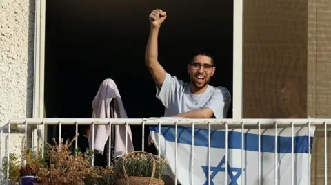 EPA/Shutterstock Released Israeli hostage Evyatar David gestures to crowds as he returns to his home in Kfar Saba, central Israel on 26 October 2025