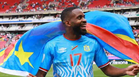 FIFA via Getty Images Cédric Bakambu celebrates on the pitch with DR Congo's national flag