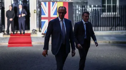 AFP via Getty Images Germany's Chancellor Friedrich Merz and France's President Emmanuel Macron in the foreground walk towards reporters