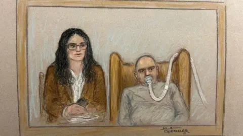 Julia Quenzler Salem Michel Al-Salem in a court sketch - he is on the right of the picture with a breathing tube on his mouth, a grey sweatshirt, he has a bald head and is slumped in an armchair. The tube makes his expression unclear. His translator, a woman with black shoulder length hair, a brown blazer, white shirt, and glasses, is sitting next to him