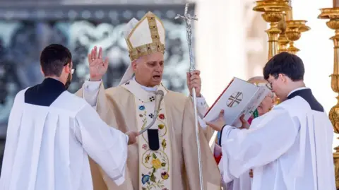 Reuters Pope Leo speaks into a microphone with one hand raised in a blessing gesture