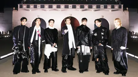 BIGHIT MUSIC/Handout via REUTERS K-pop band BTS pose for a photograph. They are standing in a line wearing black and holding microphones