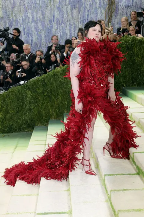Getty Images Lena Dunham wears a vivid red dress made out of feathers and sequins.