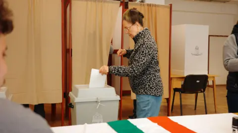 BBC Female voter with a leopard print jumper casts her ballot at a polling station in Hungary.